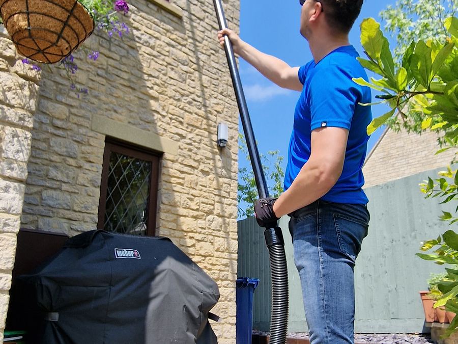 Window cleaner using a water-fed pole on a Cotswold stone house