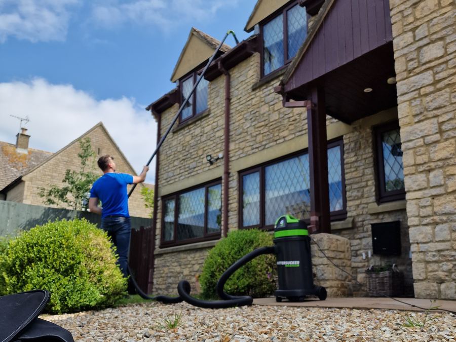 Window cleaner working on a detached house with a pole